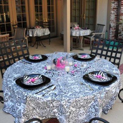 a black toile round tablecloth on a table